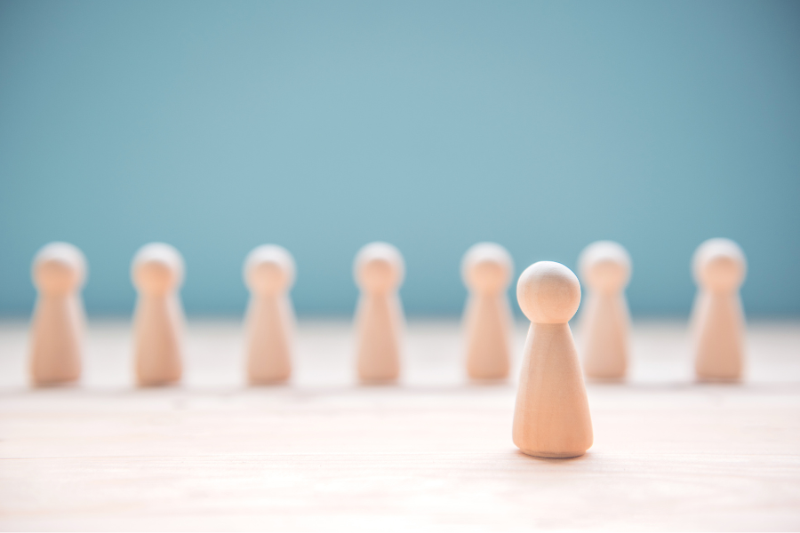 Wooden pieces in a single line with one piece in front. This image is symbolic of a leader leading a team through annual goals.